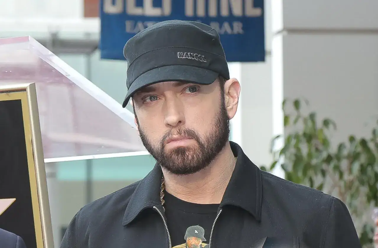 Eminem w czapce Kangol i czarnej kurtce. W tle gwiazda na chodniku. Ciekawe, ile lat ma Eminem?